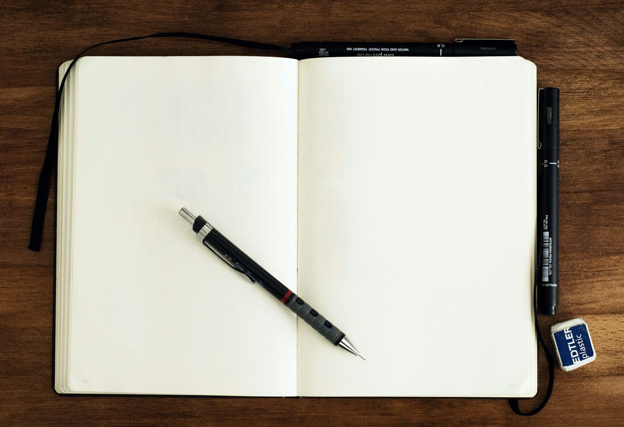 An open notebook and pen on a wooden desk