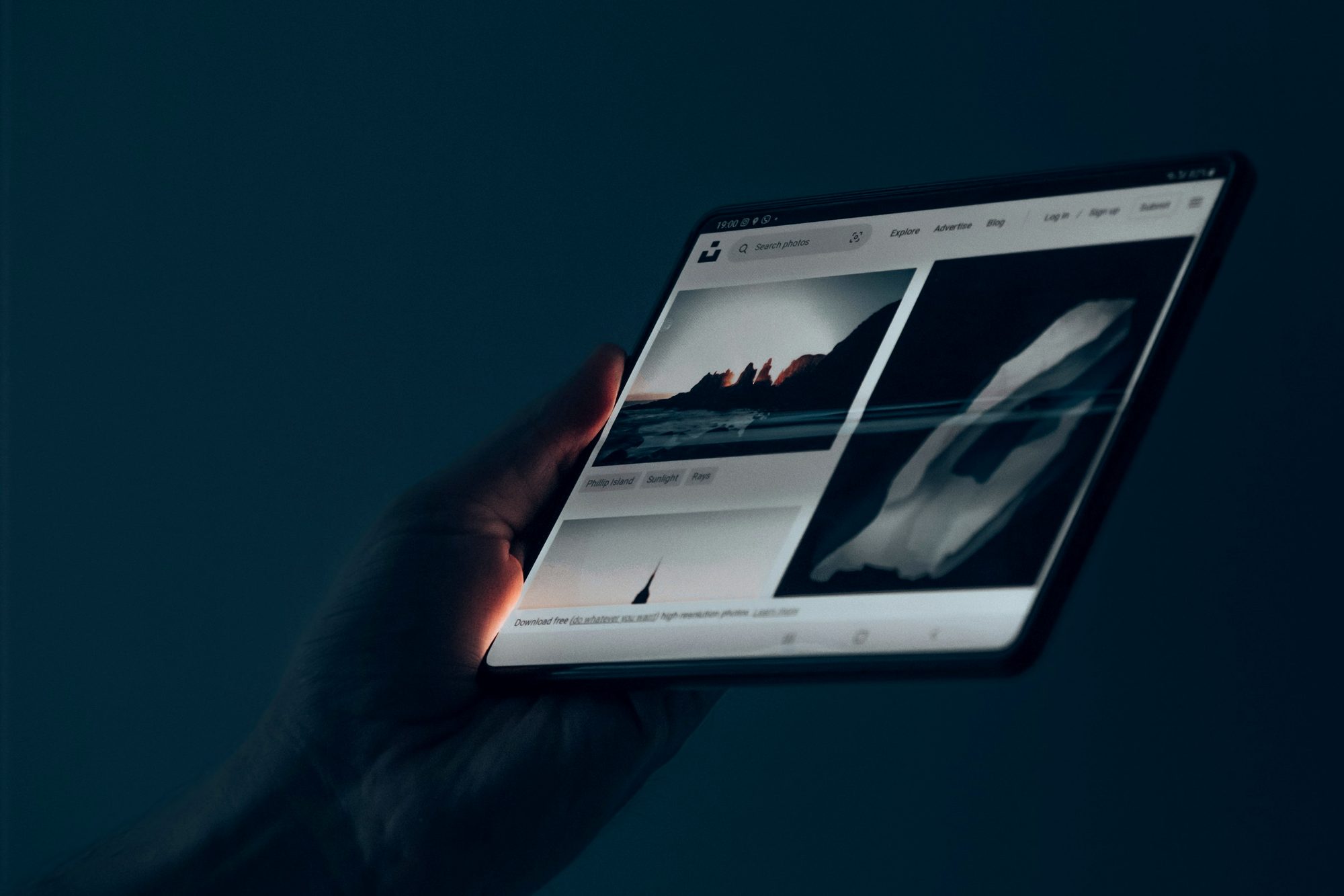 A hand holding a tablet in a dark room
