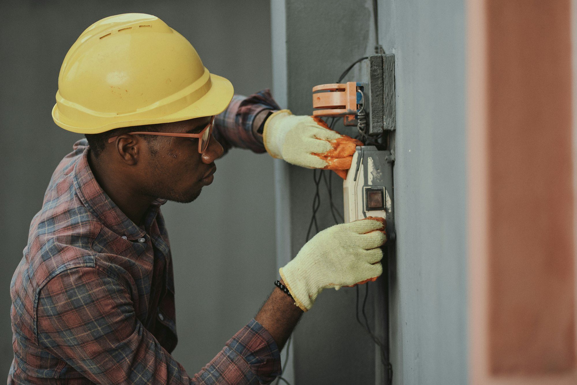 A technician in a hard hat installing equipment on a wall